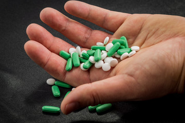 different white, green and blue pills on a clean black background.many drugs and abuse of them seriously damages health.