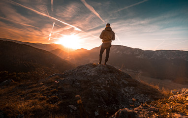 Man stands on the peak of a mountain and watching to Sun. Beautiful moment the miracle of nature.