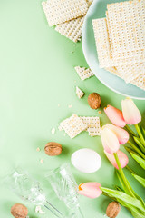 Pesah celebration concept. jewish Passover holiday background with matzo, eggs, spring flowers, wine, green background copy space top view