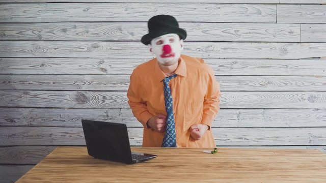 Clown businessman near the director's table swears at subordinates. Concept on angry stupid boss