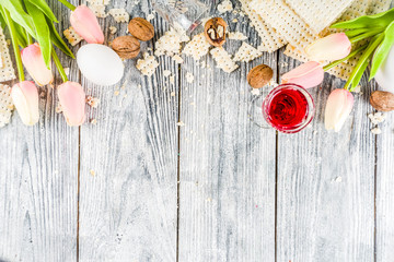 Pesah celebration concept. jewish Passover holiday background with matzo, eggs, spring flowers, wine, green background copy space top view