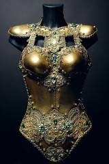 Gorgeous golden corset with precious stones, dark studio background