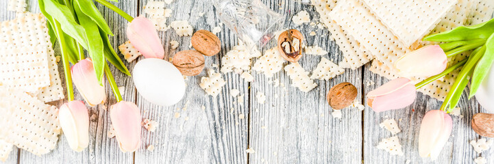 Pesah celebration concept. jewish Passover holiday background with matzo, eggs, spring flowers, wine, green background copy space top view banner