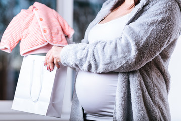 Pregnant woman with baby clothes