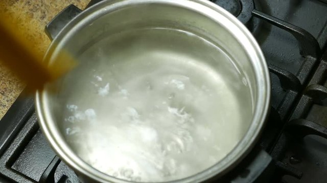 cook throws spaghetti into boiling water