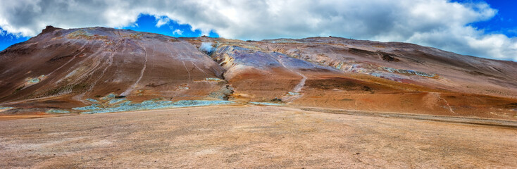 Namafjall Hverir geothermal area in Iceland. Stunning landscape of sulfur valley, panoramic view of Namafjall mountain and blue cloudy sky, travel background, tourist attraction