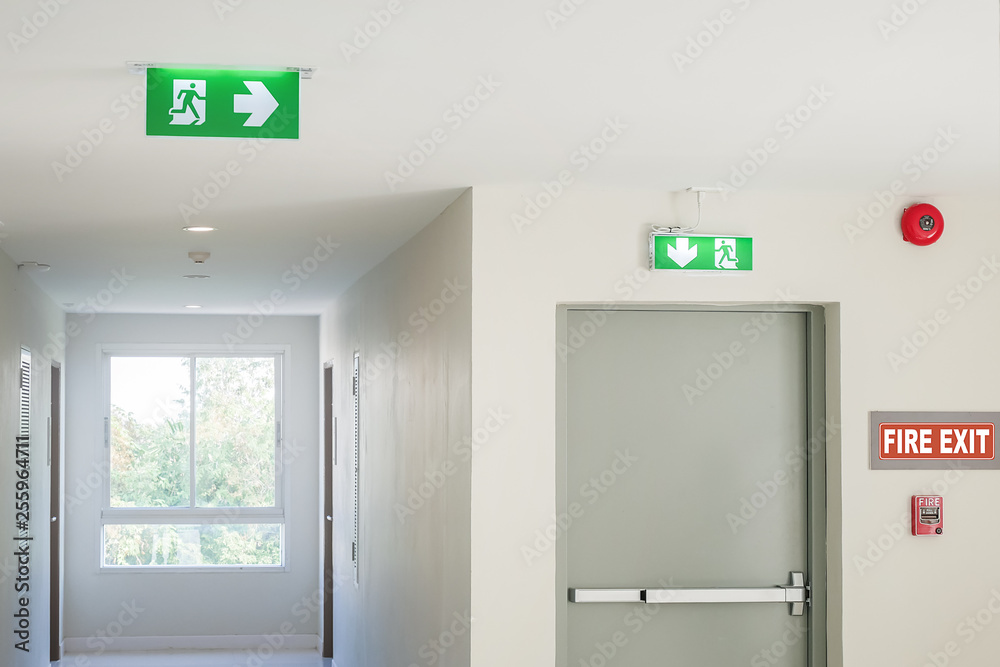 Wall mural fire exit sign with light on the path way in the hotel or office