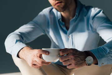 selective focus of sitting man holding coffee cup