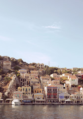 Colourful houses of the picturesque Symi island, holiday island of Dodecanese group close to Turkish coast north of Rhodes. Sunny summer evening. Dusk light. Greece. Landscape view from the water.   