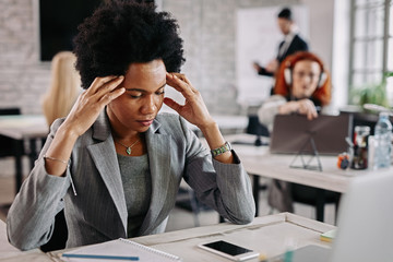 Displeased black businesswoman having a headache at work.