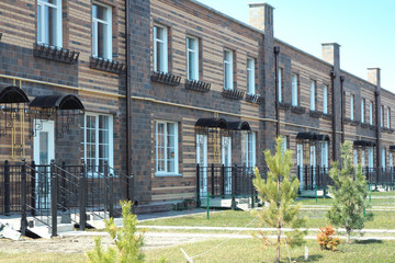 Fototapeta premium Two-storey residential building with separate entrances to the apartments and individual garages. Townhouse. Built from red, yellow and brown bricks. Copy space..