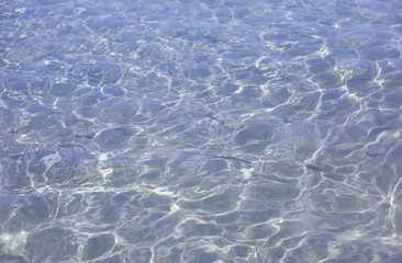 Blue transparent water surface of a Mediterranean sea on a sunny day with sun rays texture. 