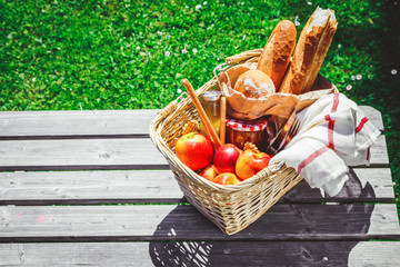 Picnic basket filled with fruit , bread and jar with apricot jam
