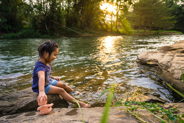 little girl playing the doll near the river