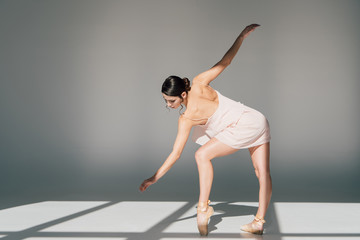 Fototapeta na wymiar beautiful young ballerina dancing in pink dress and pointe shoes