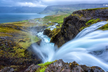 Dynjandi waterfall, Iceland, amazing landscape. Stunning view of falling water in the canyon from the top to the Dynjandisvogur bay and Arnarfjordur fjord, Westfjords of Iceland, travel background