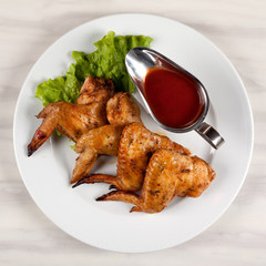 Fried chicken wings on a plate with red sauce.