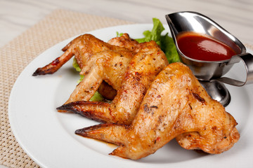 Fried chicken wings on a plate with red sauce.