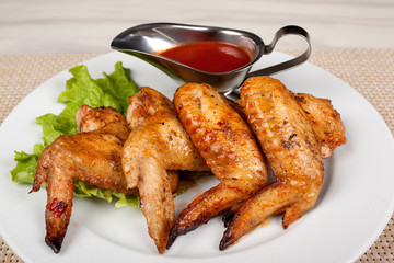 Fried chicken wings on a plate with red sauce.