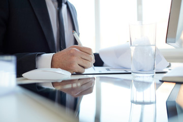 Director of business company signing financial papers or contract while sitting by desk in his...