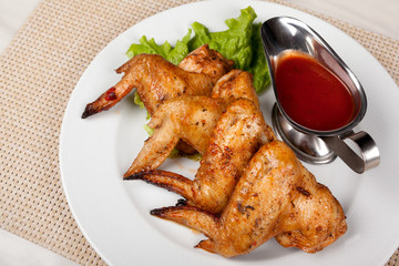 Fried chicken wings on a plate with red sauce.