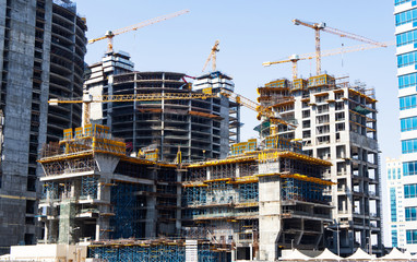 Big construction site of four modern buildings with cranes and scaffolding