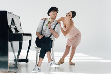 Fototapeta premium handsome musician holding rose while young ballerina touching his shoulders o