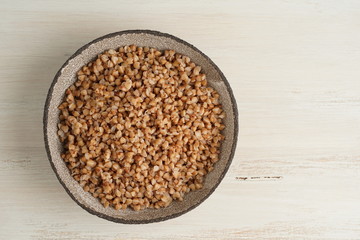 Boiled buckwheat porridge in black bowl on wooden background, top view, copy space