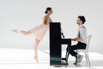 handsome musician playing while graceful ballerina dancing near piano