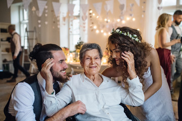 A young couple with grandmother on a wedding, posing for a photograph.