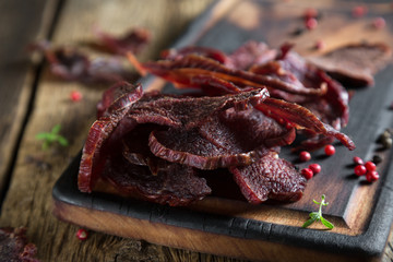 Beef Jerky on a Rustic Wooden Table - obrazy, fototapety, plakaty