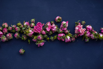 flat lay of dried pink rose buds isolated on black textured surface/ floral wallpaper background