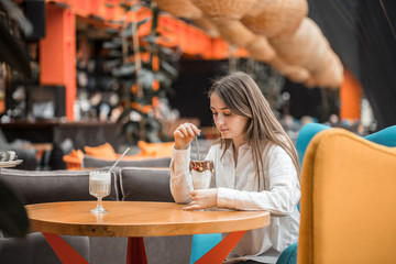Beautiful Young girl drinking milk chocolate cocktail in a cafe