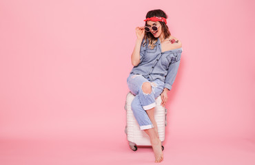 Portrait of a girl with a suitcase on a pink background