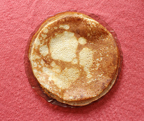 Fried pancake on a glass plate on a pink