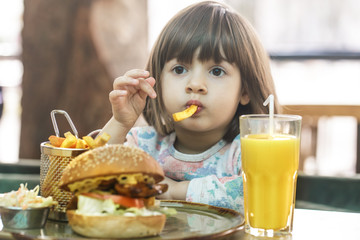 Little girl eats in a fast food cafe