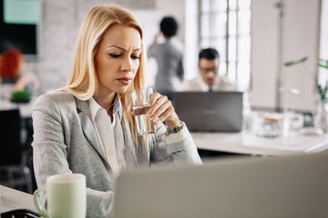 Pensive businesswoman having a glass of water while working in the office.