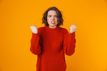 Portrait of uptight woman gesturing and yelling while standing isolated over yellow background