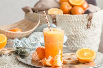 Freshly-grown organic fresh orange juice in the interior of the house, with a turquoise blanket and a basket of fruit