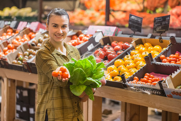 Woman in the supermarket. Beautiful young woman shopping in a supermarket and buying fresh organic vegetables
