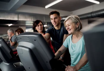 Foto op Canvas A group of seniors in gym with a young trainer doing cardio work out. © Halfpoint