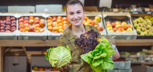 Woman in the supermarket. Beautiful young woman shopping in a supermarket and buying fresh organic vegetables