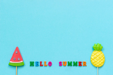 Hello summer colorful text, pineapple and watermelon lollipops on stick on blue paper background. Concept vacation or holidays Creative Top view Copy space Template Greeting card, postcard