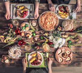Holiday friends or family at the holiday table with rabbit meat, vegetables, pies, eggs, top view.