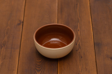 Empty ceramic bowl on wooden table, top view.