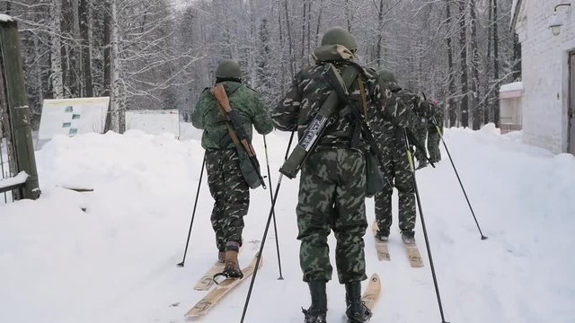 Military on skis with a guns. Clip. Group of soldiers on skis in the woods