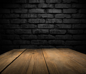 Selected focus empty brown wooden table and wall texture or old black brick wall blur background...