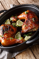 quarter chicken leg baked with tamarind sauce and lime closeup in a pan. vertical