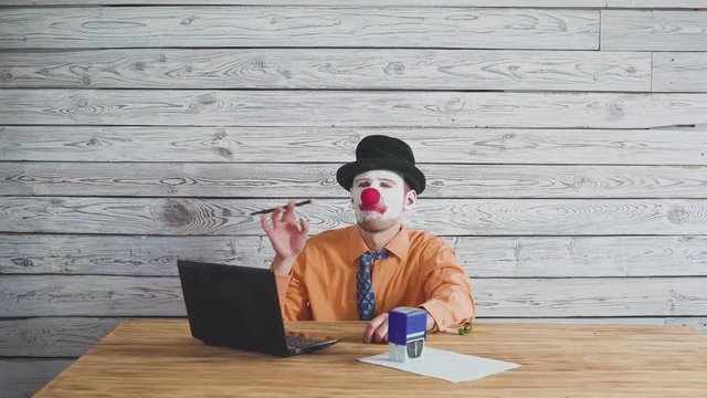 Office worker clown is funny signing and stamping a document. Concept on a stupid boss