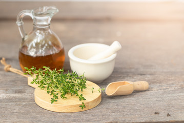 fresh thyme branch  on wooden background over blur white mortar and oil in jar